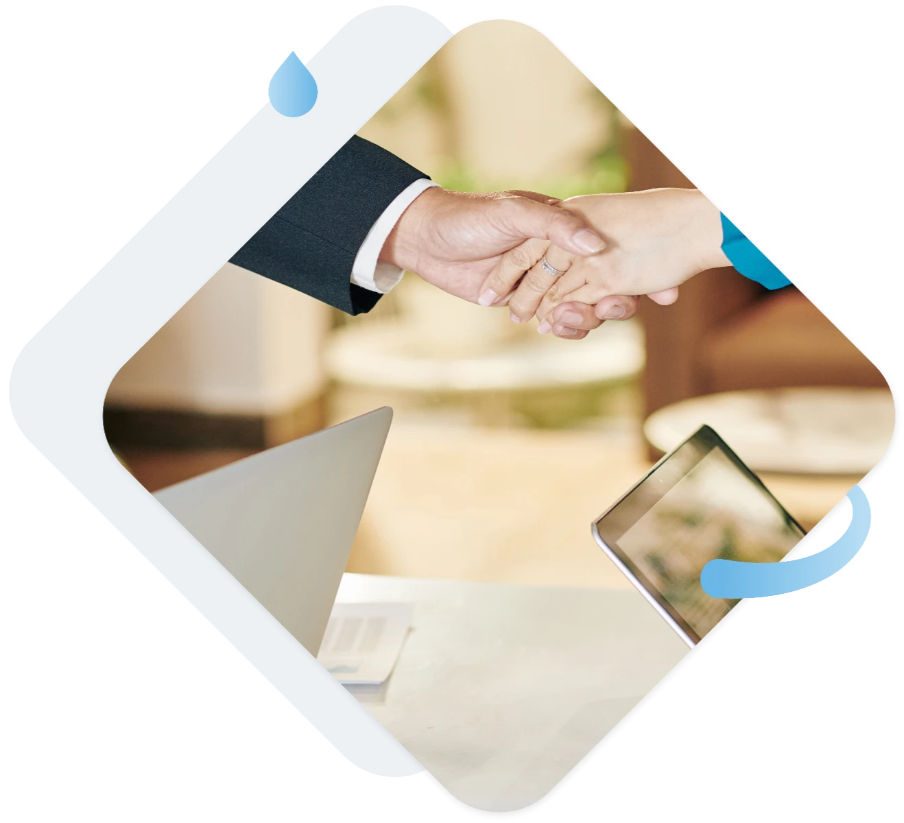 Dwie osoby w biurze ściskające sobie ręce nad stołem z laptopem i tabletem, symbolizujące profesjonalne doradztwo