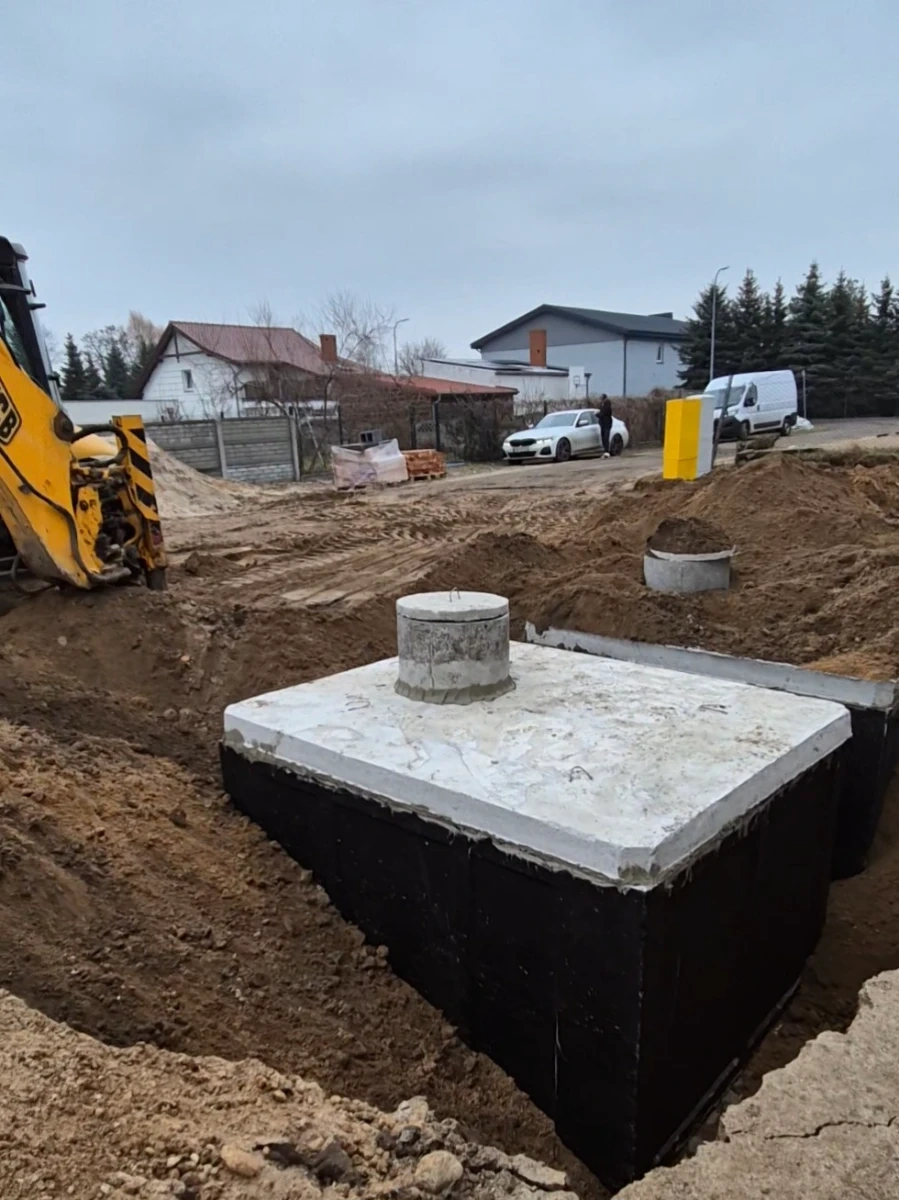 Szambo betonowe osadzone w wykopie, widoczny betonowy właz przygotowany do instalacji
