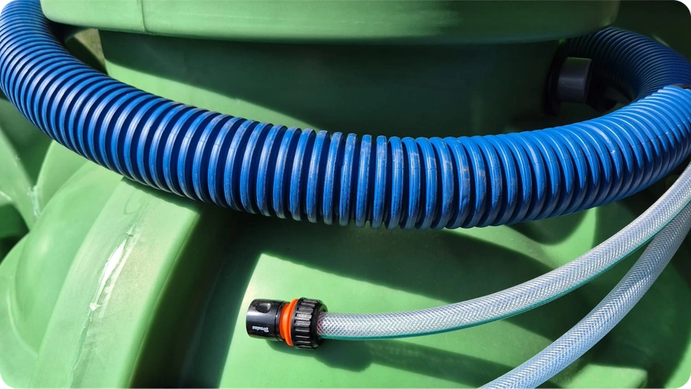 Zielony zbiornik na deszczówkę z zamocowanymi wężami