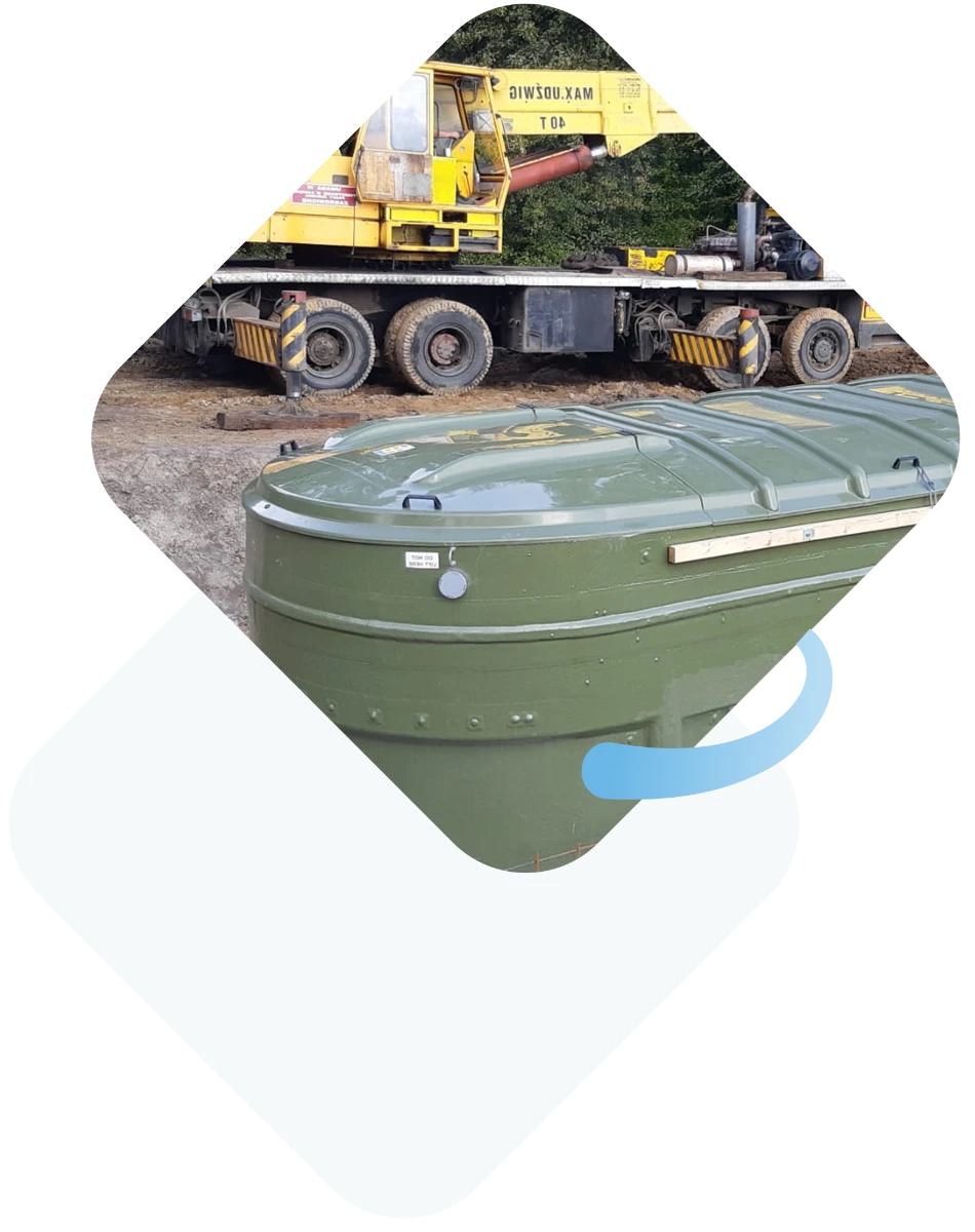 Zielony zbiornik przydomowej oczyszczalni ścieków ustawiony na placu budowy obok żurawia