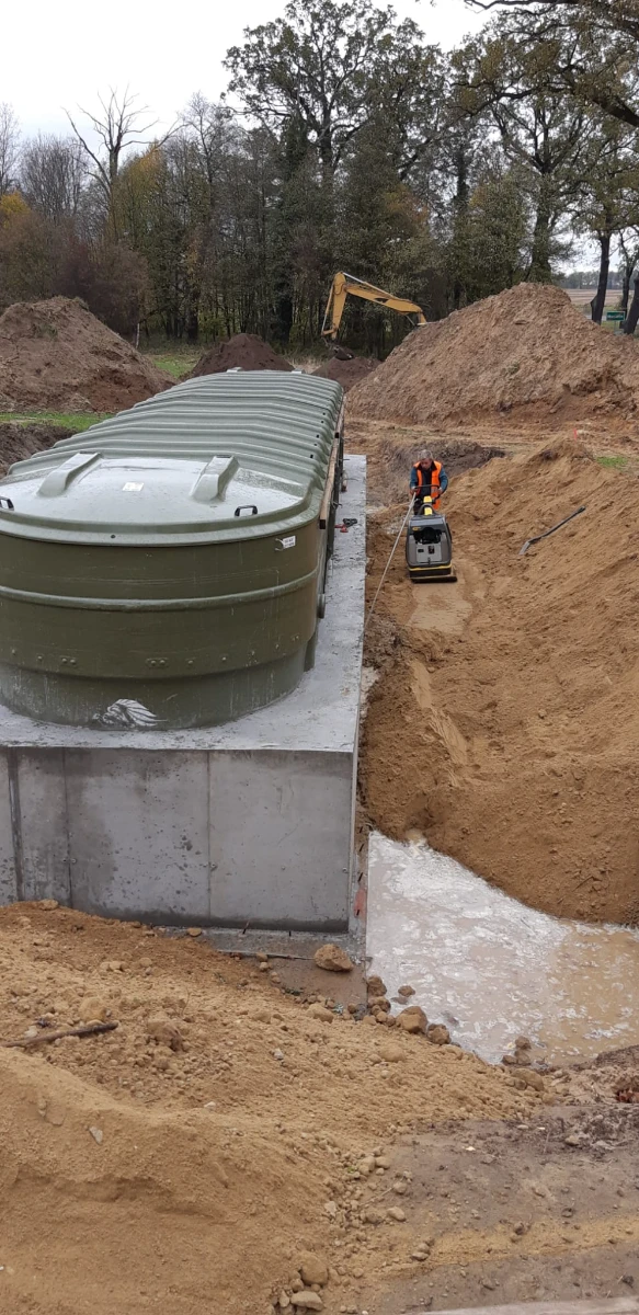 Montaż szamba ekologicznego na betonowej płycie, ustawianie zielonego zbiornika i zagęszczanie gruntu