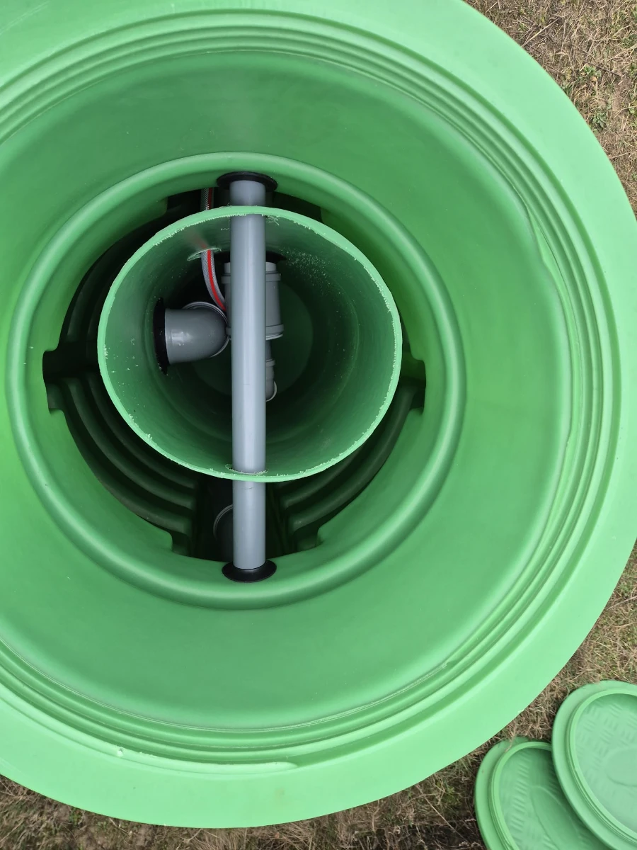 Wnętrze zielonego zbiornika przydomowej oczyszczalni ścieków z instalacją rurową